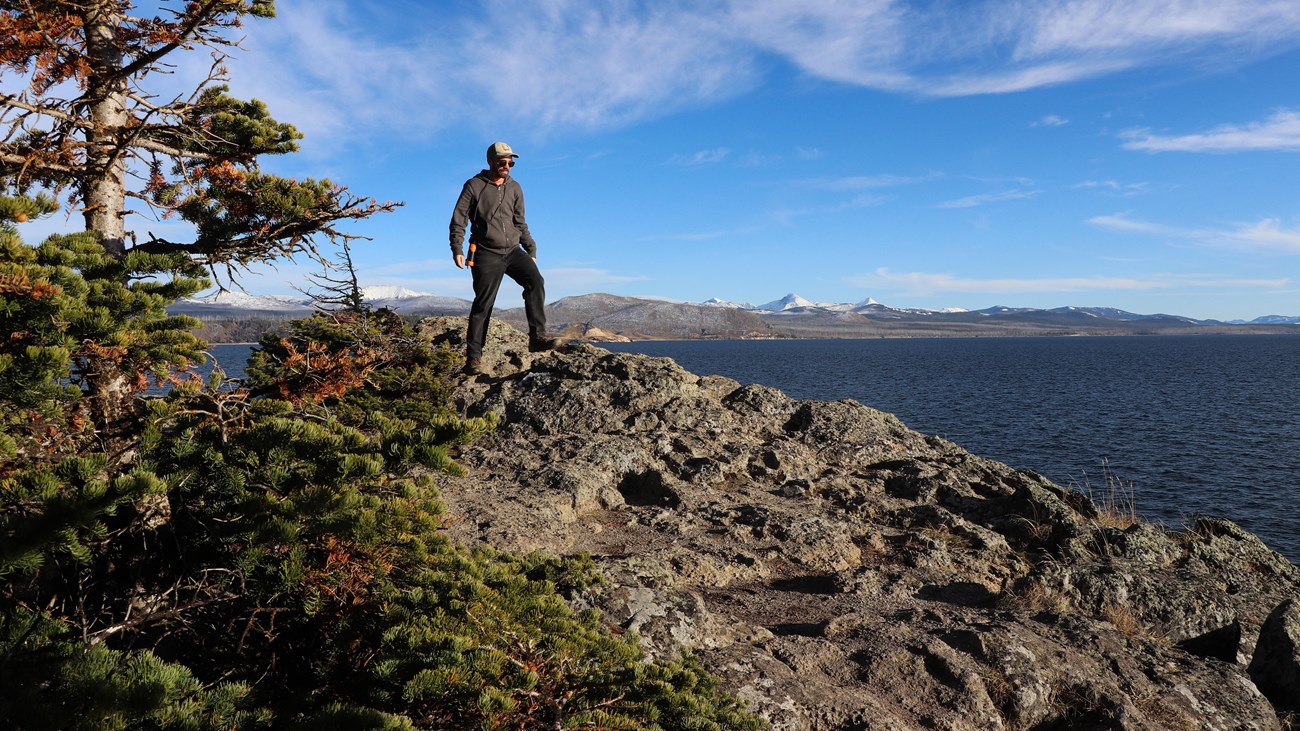 A hiker on the rocky shore at Storm Point above Yellowstone Lake